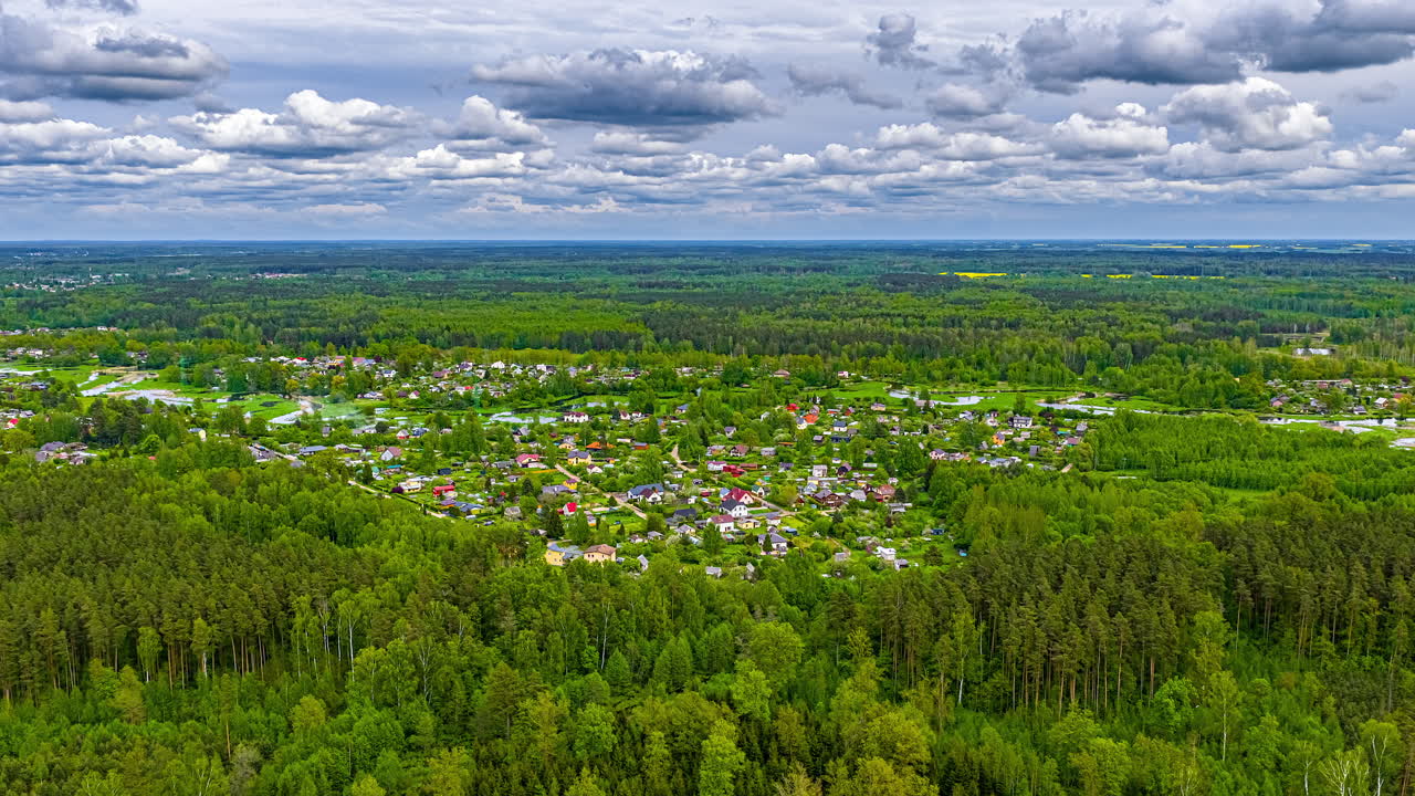 A town or planned community in a European countryside forest as summer with a cloudscape overhead - forward areal hyper lapse