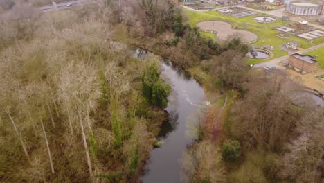 río a través del bosque al lado de la planta de tratamiento de aguas residuales en thetford, norfolk - toma aérea de vuelo de drones: área rural con carretera