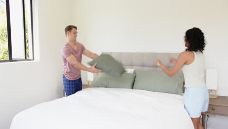 making bed, young man arranging pillows in bright, modern bedroom, at home