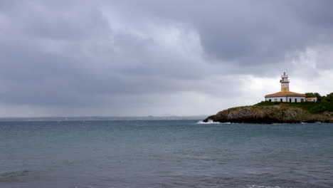 Olas-Golpeando-Las-Rocas-En-Una-Isla-Con-Un-Faro-En-Un-Día-Nublado-De-Otoño