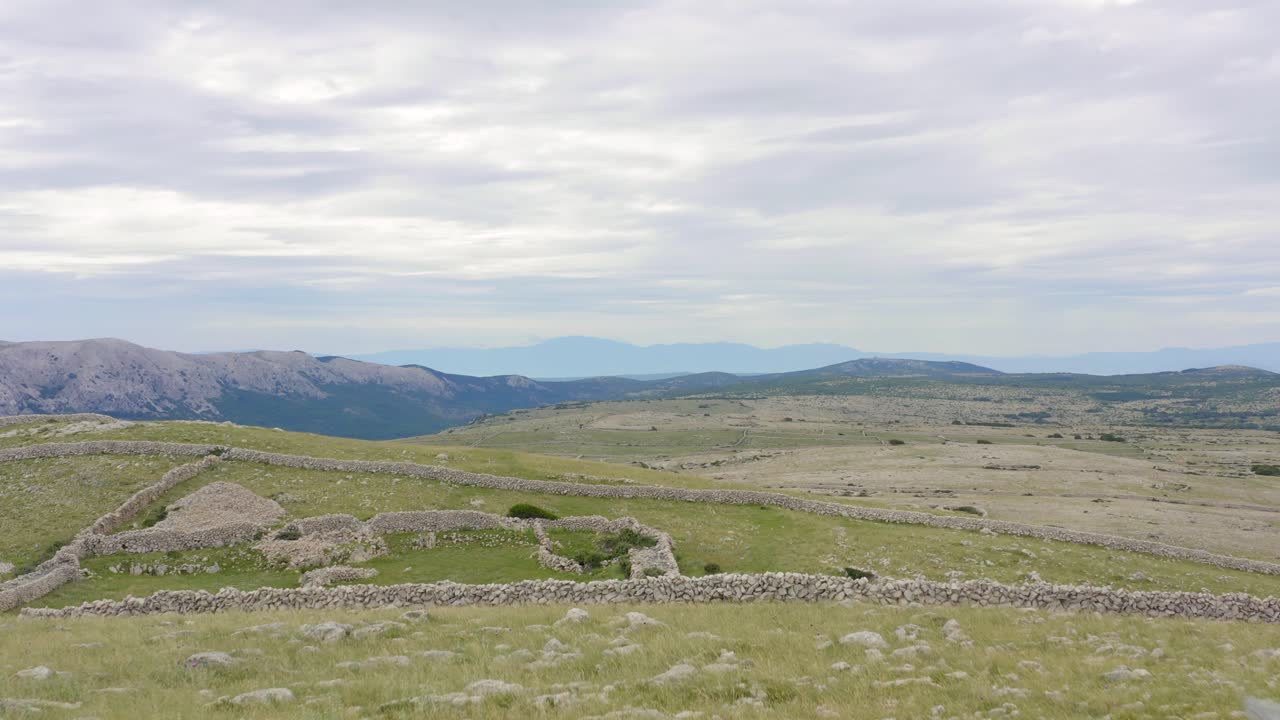 크로아티아 크르크 섬의 바위에 나무 십자가가 있는 무성한 바위 트레일 - 드론 샷