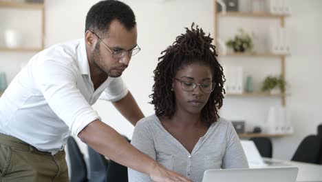 Front view of two concentrated people working with laptop