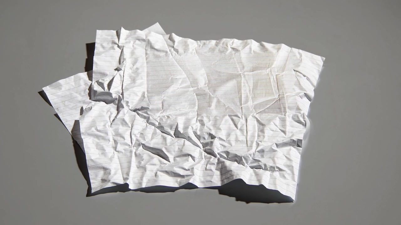 Crumpled Piece of Lined Paper on a Grey Surface