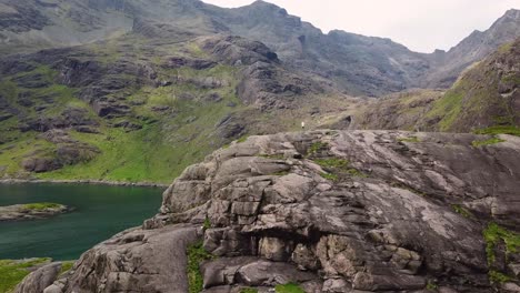 hiker on clifftop in western scottish highlands, overlooking ocean, aerial view