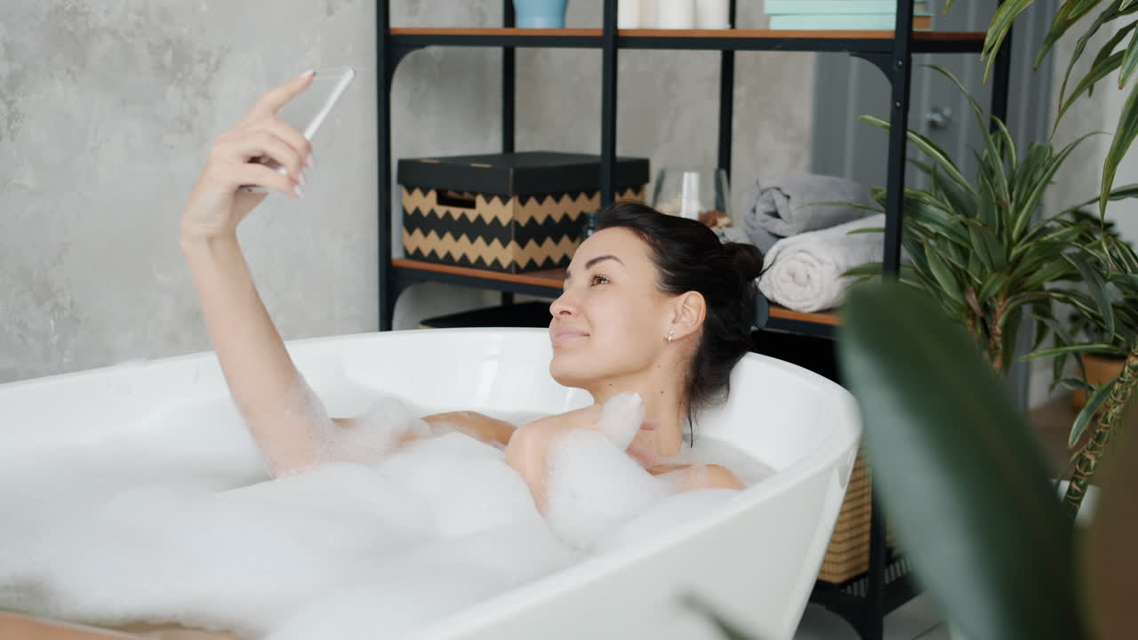 거품 욕조에서 셀피를 찍는 여자