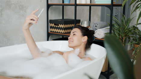 woman taking a selfie in a bubble bath