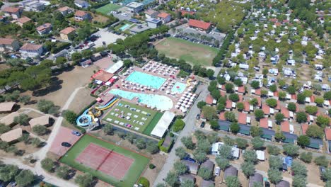 aerial tilt down revealing huge swimming pool with colourful waterslides