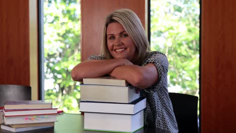 smiling mature student leaning on pile of books
