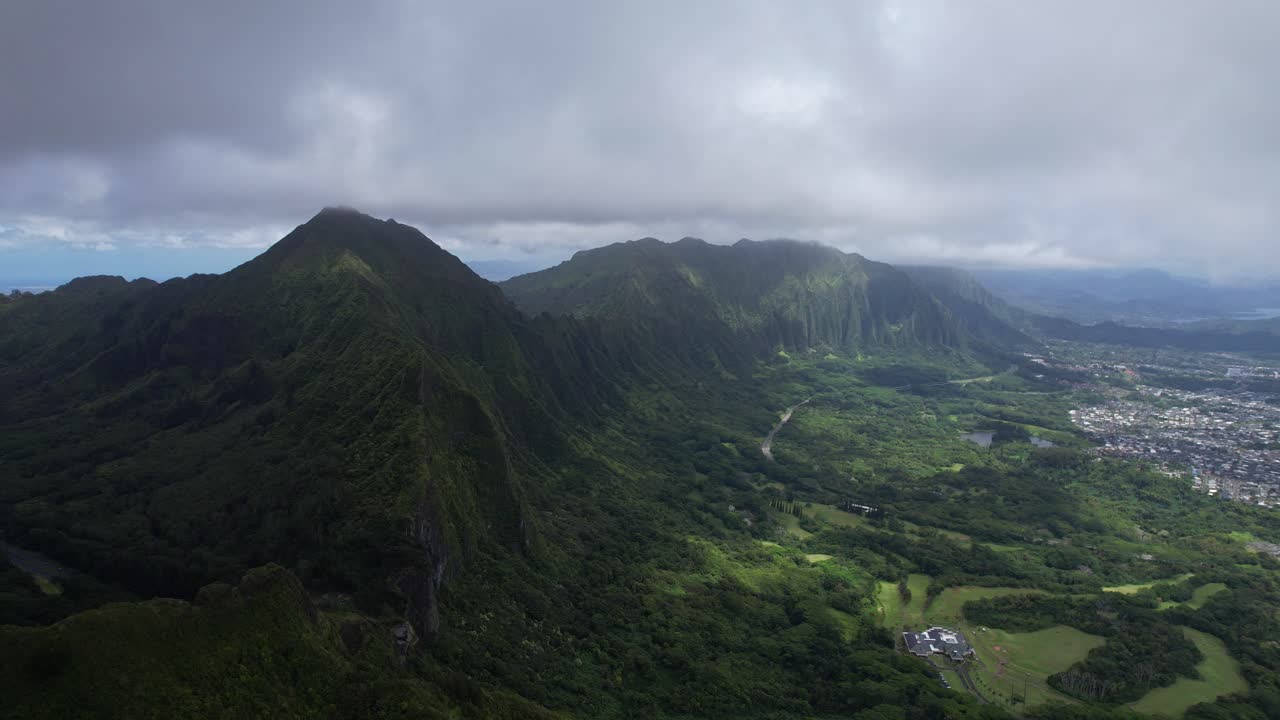 Nu&lsquo;uanu Pali - overlooking cliff with city scape in the distance - flying backwards
