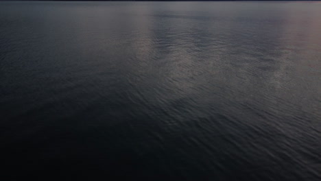 Aerial-view-tilting-up-flying-over-lake-Thun-just-after-sunset