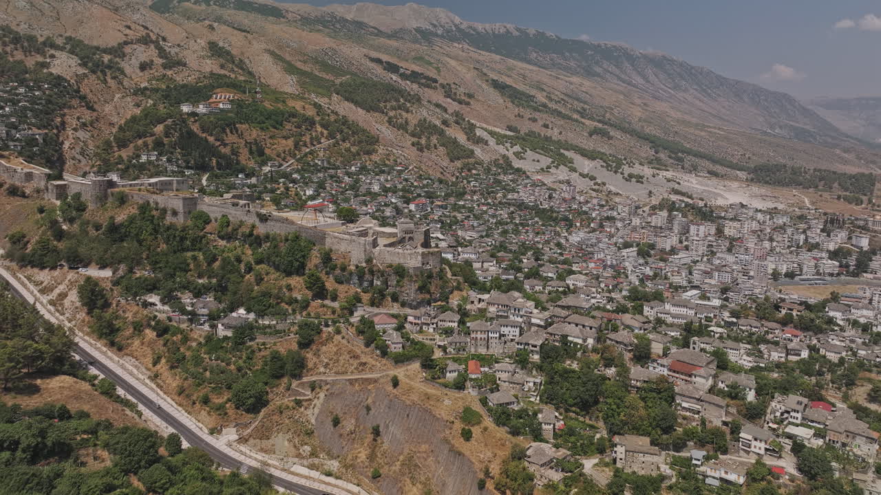Gjirokastra, Albania. Sobrevuelo aéreo v17 de un sitio patrimonial en ladera, mostrando el castillo histórico, la torre del reloj, el barrio residencial y la plaza del pueblo - Filmado con Mavic 3 Pro Cine - 14 de julio de 2024