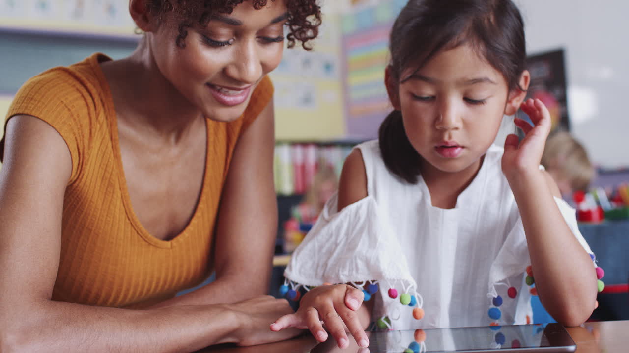 maestra de escuela primaria y alumna dibujando usando tableta digital en el aula