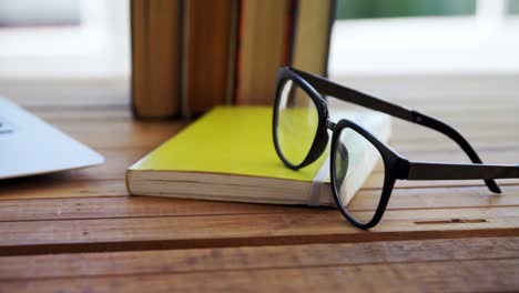 portátil, libros y gafas en una mesa de madera 4k