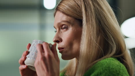 mujer relajada bebiendo una taza de té en el retrato de la oficina tardía. mujer pensativa descansando