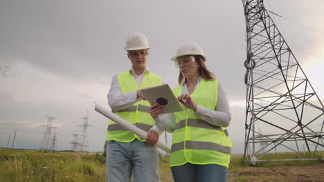 engineer and supervisor with tablet pc and the drawings are about lines and transmission towers and discuss the expansion plan and transportation energy for towns and cities