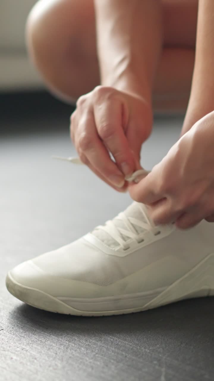 Primo piano di mani che allacciano scarpe da ginnastica bianche