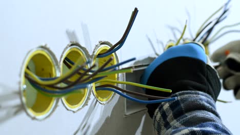 electrician sorts out wires in outlet