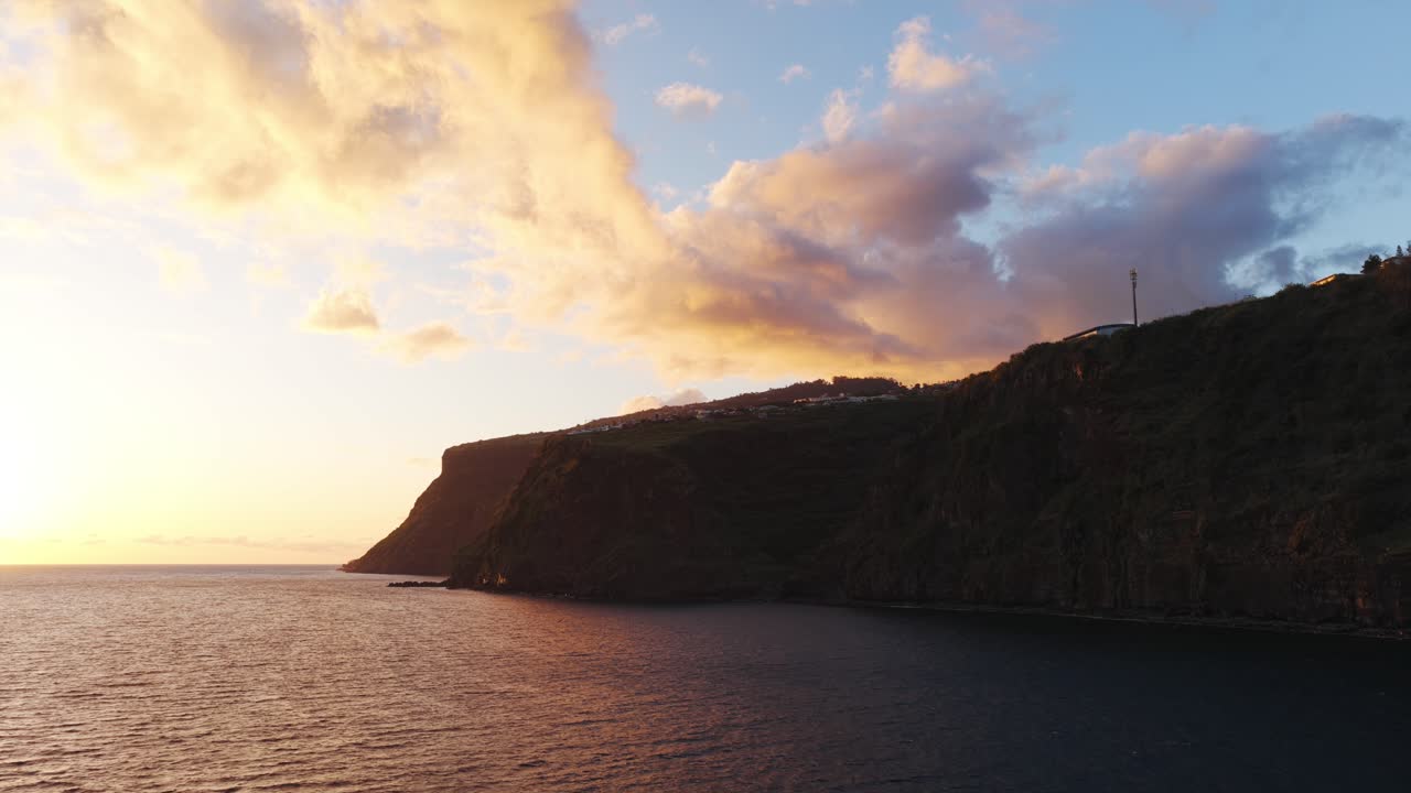 O pôr do sol ilumina os penhascos do litoral da Calheta na Ilha da Madeira, Portugal, com cores douradas e quentes
