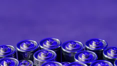 silver batteries aa and aaa in neon light close-up. double-a battery is a standard size single cell cylindrical dry battery. batteries are common in portable electronic devices. an aa battery is composed of a single electrochemical cell that may be either a primary battery or a rechargeable battery.