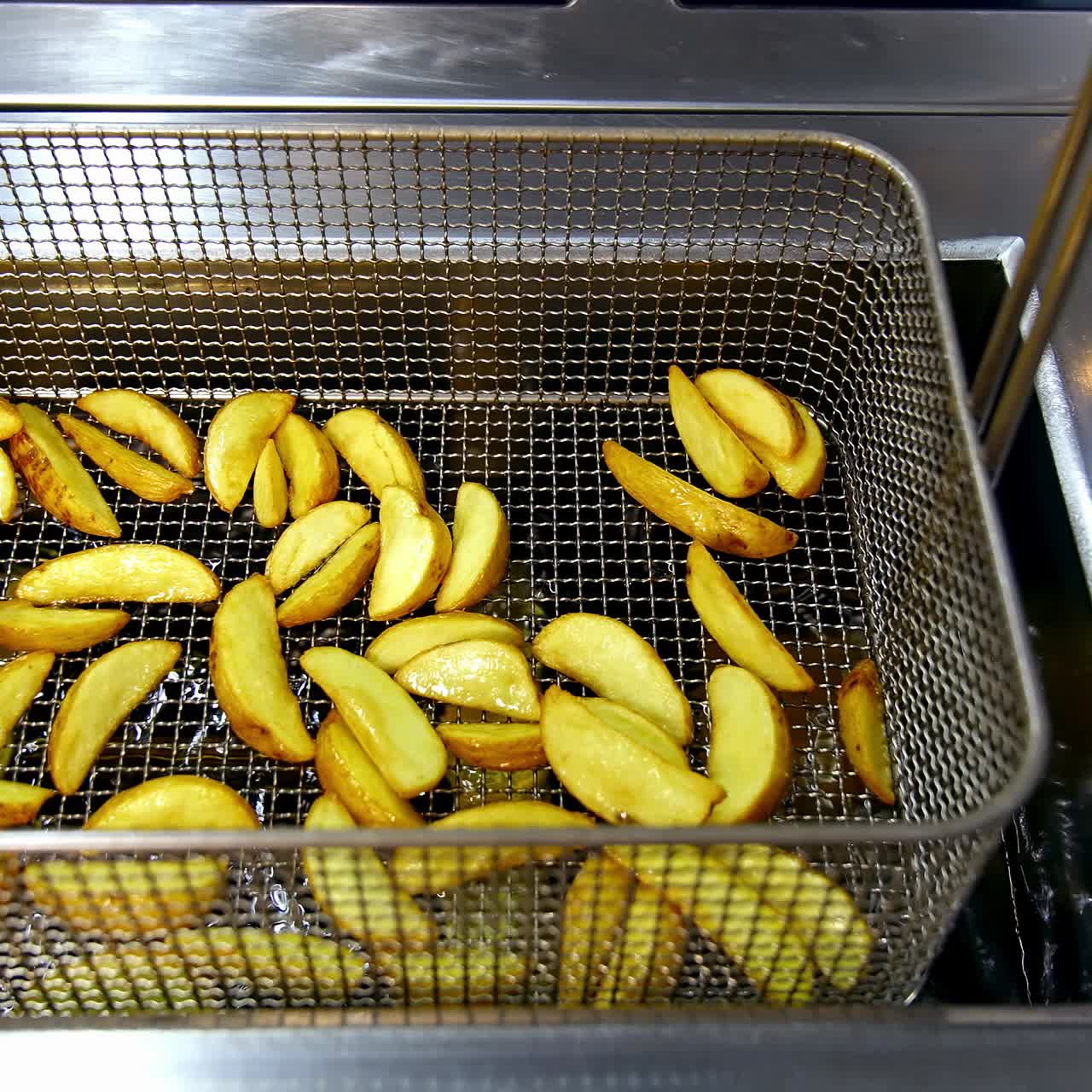 French fries cooking. Grid with strips of potato lowered into boiling oil. The concept of fast food, delicious unhealthy food