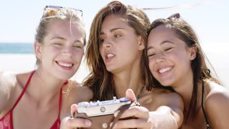 cerca de tres amigas adolescentes tomando una fotografía selfie con una cámara vintage