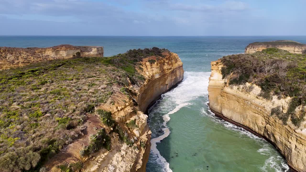 Aerial footage of Loch Ard Gorge's rugged cliffs and turquoise waters under clear skies, showcasing natural beauty and dramatic coastal landscapes