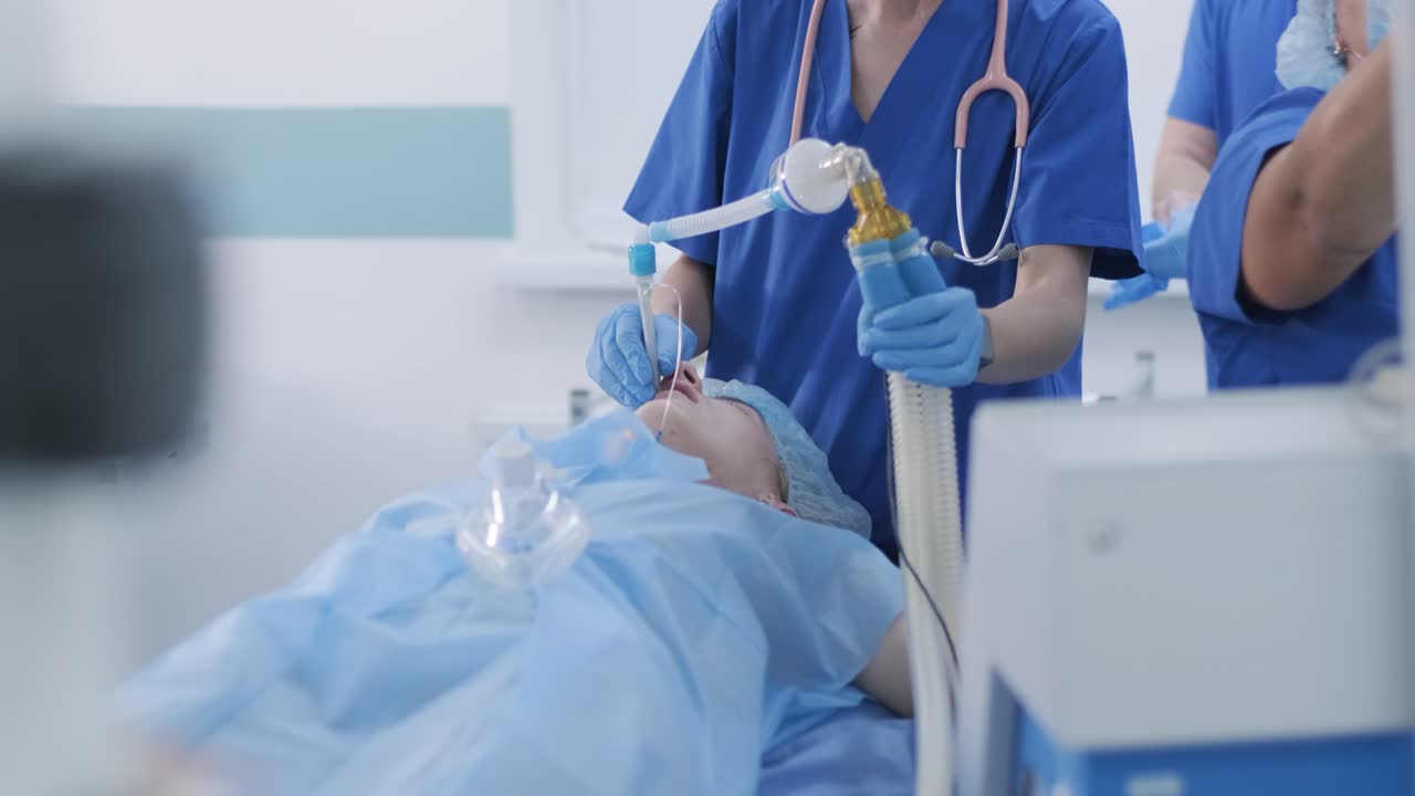 The anesthesiologist and medical team prepares female patient for surgery, puts patient into anesthesia, regulates oxygen mask, endotracheal tube. Surgery. Anesthesia
