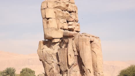 ruins of the giant statue of pharoah with mountains in the background at the colossi of memnon in luxor egypt