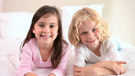 Smiling-siblings-lying-on-a-bed