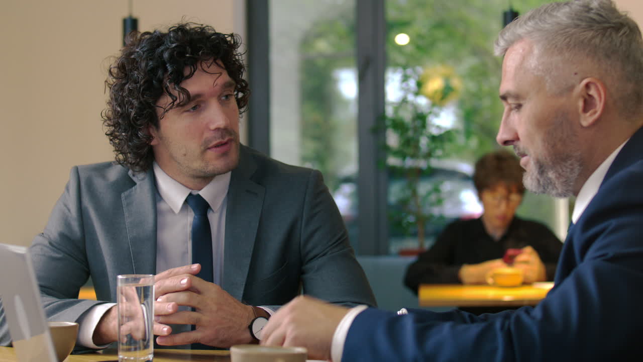 Businessman Discussing Documents with Senior Executive in Cafe