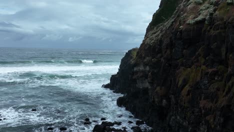 slow motion drone footage of waves crashing to cliffs on a stormy day