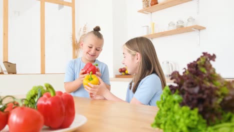 little brother and sister in blue tshirts are sitting in the kitchen and eating fresh vegetables little brother and sister in blue tshirts are sitting in the kitchen and eating fresh vegetables the concept of a happy child healthy food for children