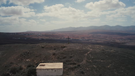 drone shot of a cross at top of a mountain in fuerteventura