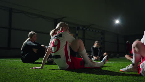 women's soccer team stretching on an indoor field