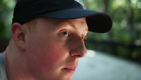 close-up of young caucasian male sitting in a park and looking around