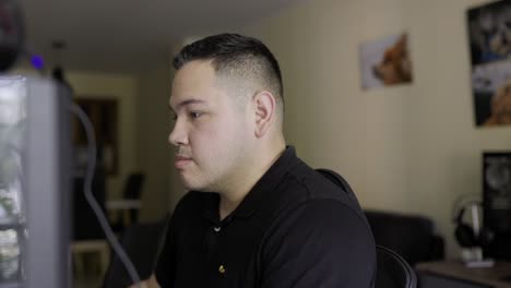 super tiro apretado de un joven latino de piel blanca haciendo algún trabajo en una computadora de escritorio