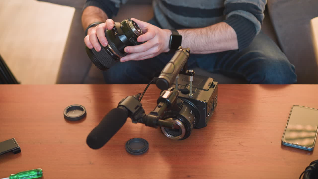 close-up of hands placing camera lens, adjusting microphone, preparing equipment for video production. organizing camera setup with microphone and gear for professional filming and recording