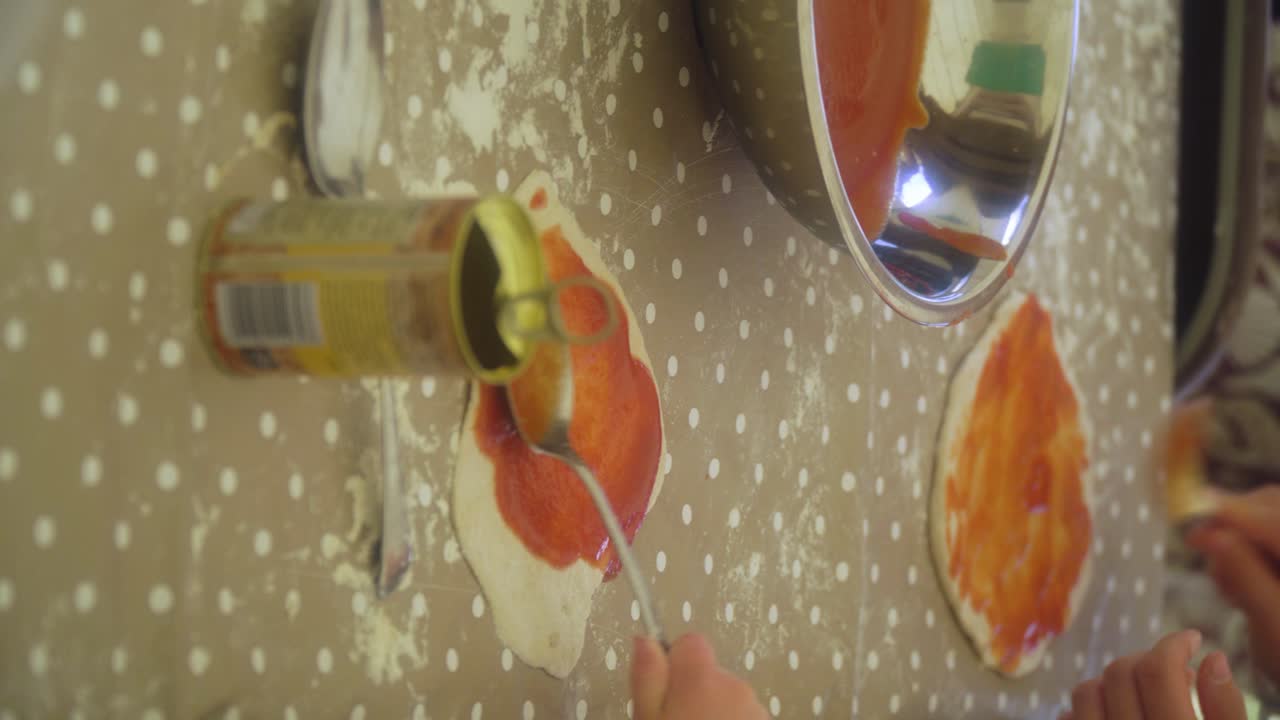 clase de horneado de coque hacer pizza desde cero tener la masa lista en la mesa y esparcir la salsa de tomate del tazón sobre la base de la pizza cerrar las manos tazón de plata con video vertical de salsa