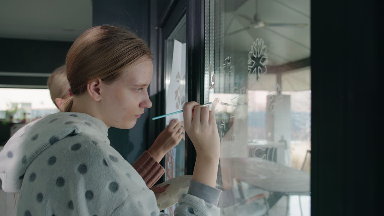 Woman painting snowflakes on window