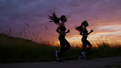 two women running in silhouette at sunset