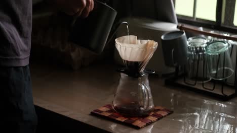 gooseneck kettle pouring hot water into pour-over coffee brewing setup - medium static shot