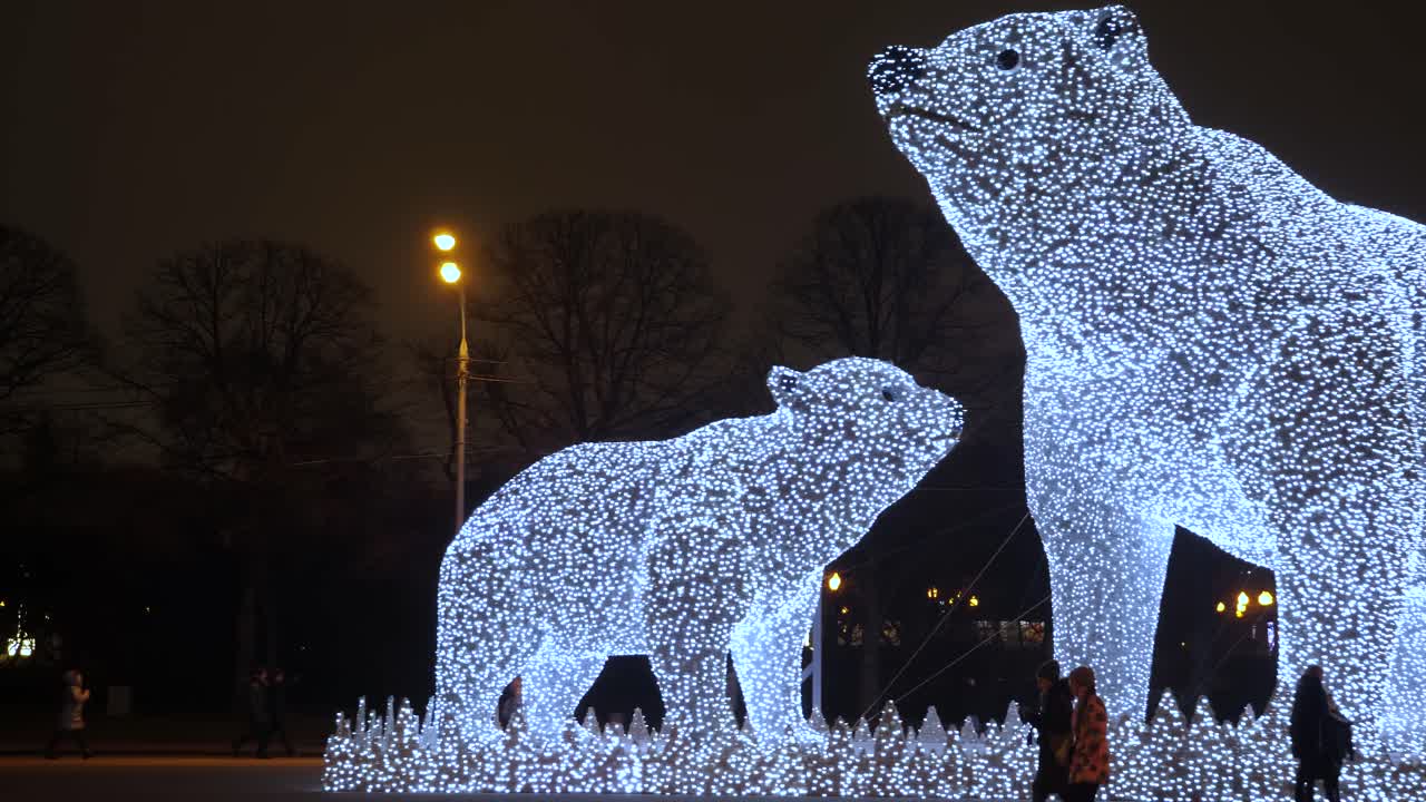 The enchanting Christmas lights in Moscow illuminate a stunning giant polar bear, creating a magical winter atmosphere. Visitors gather to admire the festive decorations in the city.