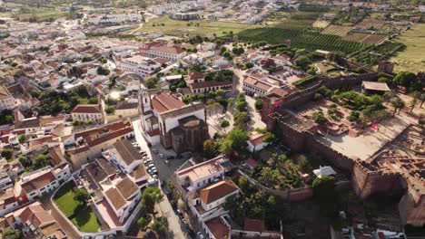 Aerial-cityscape-of-the-medieval-town-of-Silves-in-Portugal,-showing-building-and-castle-walls,-bright-daylight