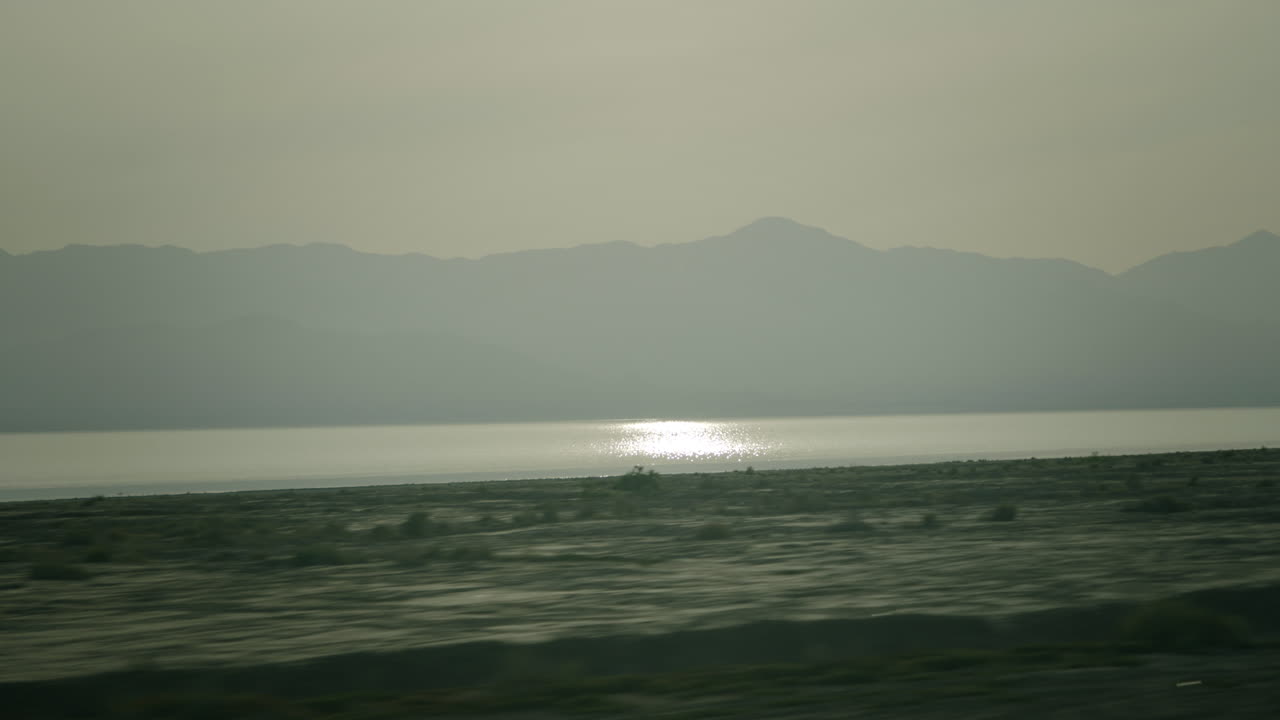 Hazy Mountains and Lake with Sun Reflection