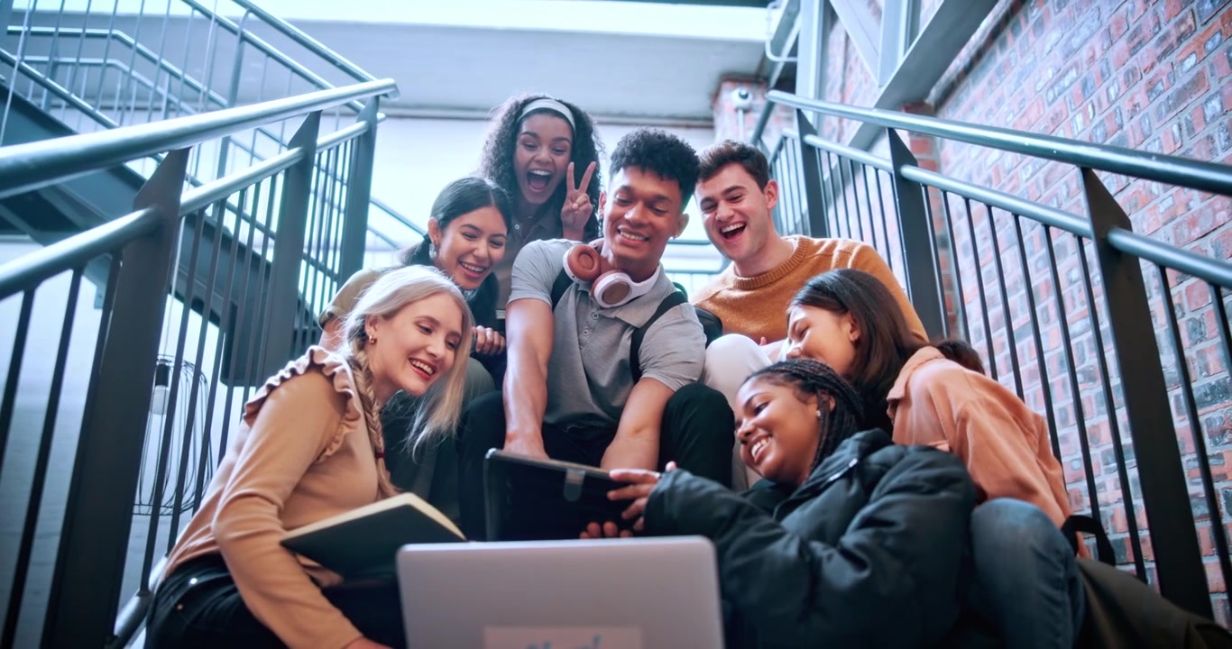 Gruppo eterogeneo di studenti che collabora a un progetto sulle scale del campus