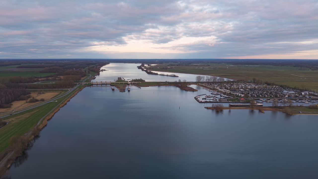 Aerial view of the Nijkerkernauw waterway at sunset, the road bridge over the canal dividing the two provinces and a recreational park with a boat dock. Dutch landscape.