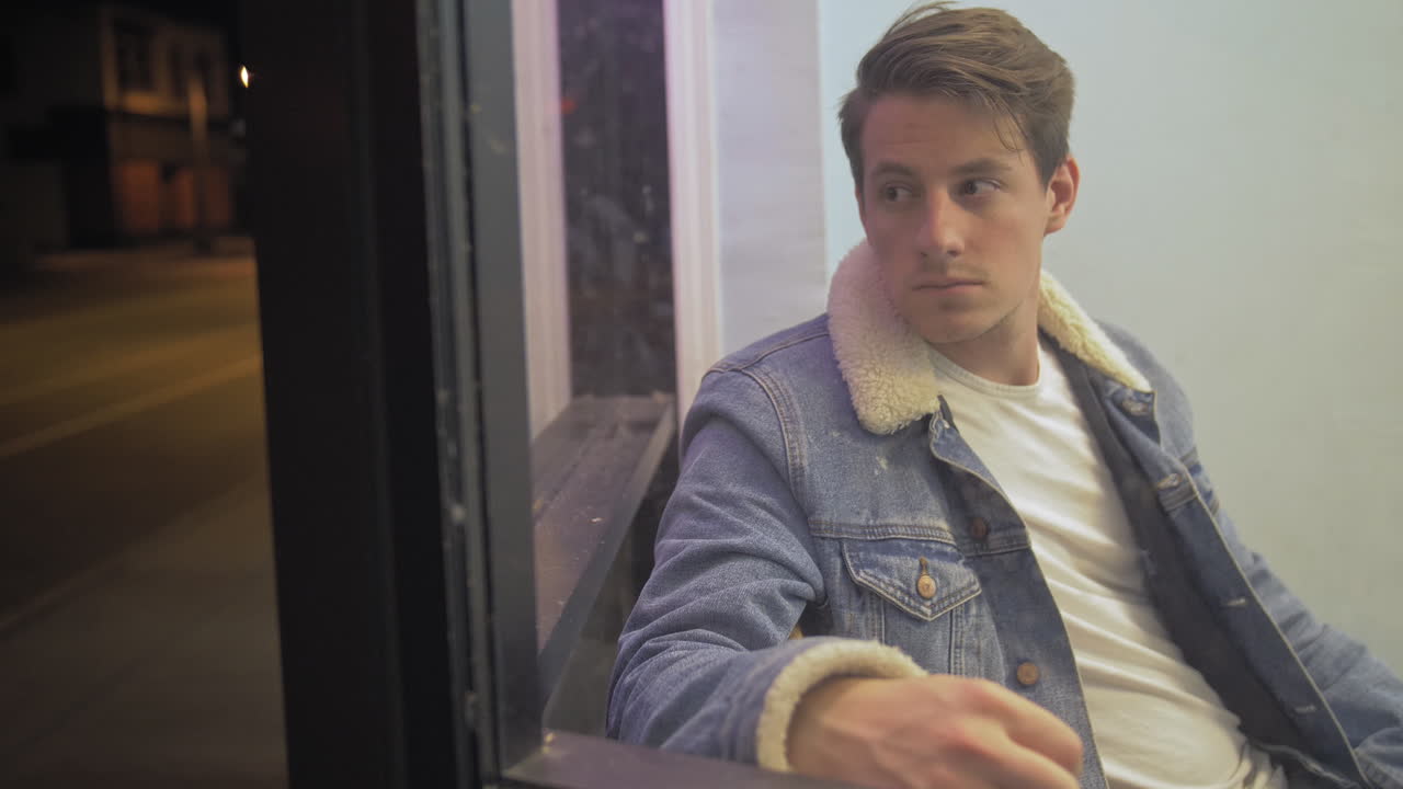 밤에 창밖을 슬프게 쳐다보는 백인 남자