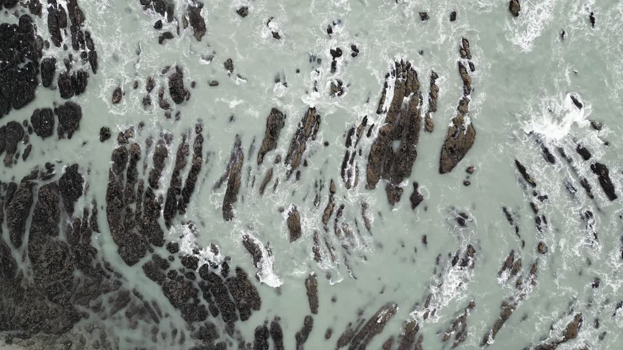 tomada de drone en cámara lenta de 4k de las olas que se estrellan en las costas rocosas debajo de gaviotas volando