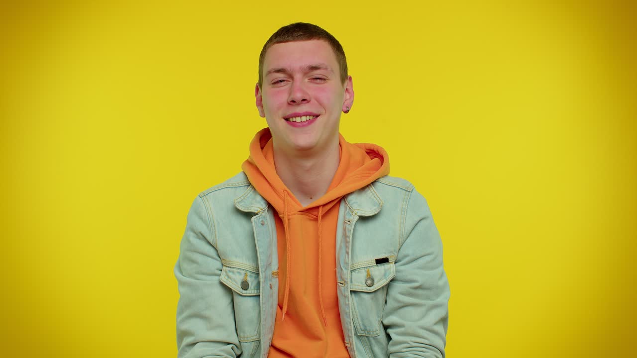 미소 짓는 장난스러운 행복한 남자가 눈을  ⁇ 이고, 이빨이 있는 미소로 카메라를 쳐다보고, 눈을  ⁇ 고 유혹합니다.