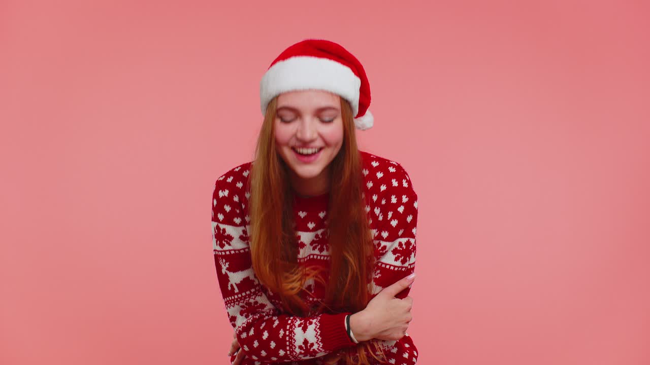 Lovely positive adult girl in christmas sweater laughing out loud after hearing anecdote funny joke